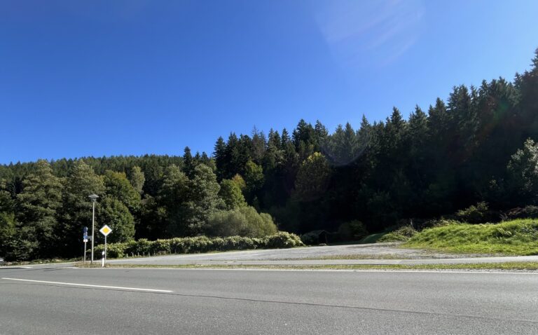 Bild eines Parkplatzes mit Schotter von der gegenüberliegenden Straßenseite aus fotografiert